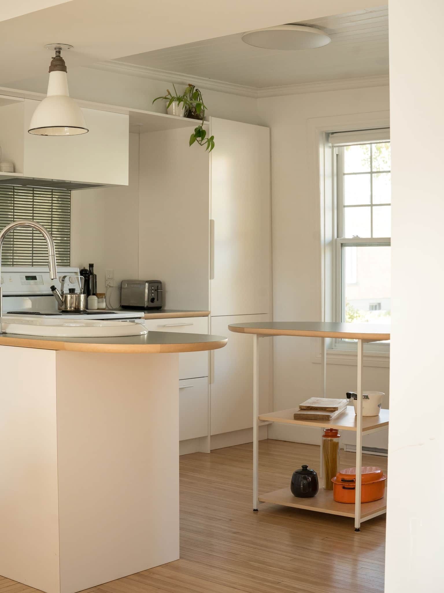 Een moderne keuken met een centraal eiland, een inbouwoven en een raam dat voor natuurlijk licht zorgt.