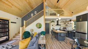 Une cuisine moderne dotée d’un îlot central, d’appareils électroménagers intégrés et d’un plafond en bois.
