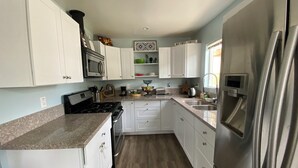 Una cocina moderna con armarios blancos, un refrigerador de acero inoxidable, un microondas y una estufa.