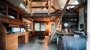 A rustic kitchen with wooden cabinets, a loft bed, and a large barrel. - Relax at this cozy, well appointed cabin located in sunny Knik, Alaska.  (Wasilla)