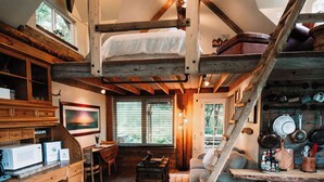 A rustic cabin interior with a loft bed, wooden furniture, and a kitchen area. - Relax at this cozy, well appointed cabin located in sunny Knik, Alaska.  (Wasilla)