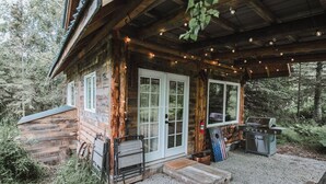 A rustic cabin with a covered porch, a grill, and a fire extinguisher. - Relax at this cozy, well appointed cabin located in sunny Knik, Alaska.  (Wasilla)