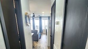 A hallway with a wooden floor, black doors, and a ceiling light fixture.