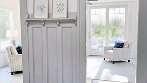 A room with a white door leading to an outdoor patio area. There are two framed floral artworks on the wall above the door. - The Blueberry House - Spacious, Family & Pet-Friendly Retreat near Sebago Lake (Sebago)