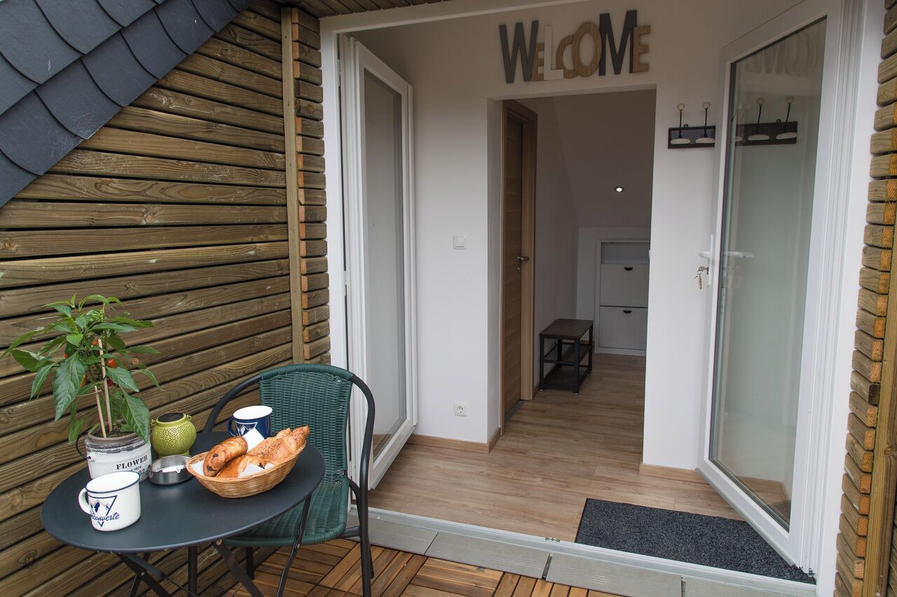 A cozy outdoor seating area with a table, chairs, and a welcome sign.