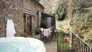 A stone building with a hot tub, outdoor seating, and a small garden area.