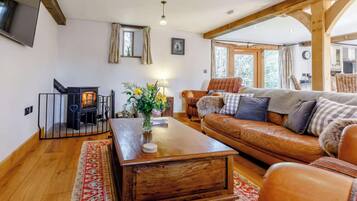 A cozy living room with a wooden coffee table, leather sofa, and a fireplace.