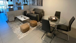 Una sala de estar moderna con sofá, mesa de centro y comedor con sillas.