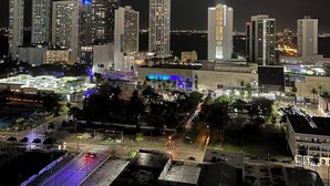 Un paisaje urbano nocturno con edificios altos y una intersección bien iluminada.