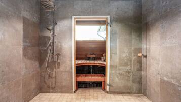 Relax in a serene space with a bench and showerhead, plus a small table and chair.