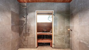 A walk-in shower with a wooden bench, tiled walls, and a visible window. - Villa Syreeni - Seafront/Jacuzzi (Porvoo)