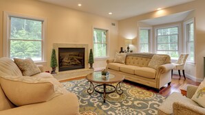 A spacious living room with a beige sofa, a round coffee table, and a fireplace. - Glen Spey Home w/ Grill ~ 5 Mi to Delaware River (Glen Spey)
