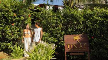 A sign for 'UNAI' with a palm tree logo, surrounded by lush greenery and plants.