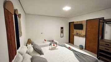 A hotel room with a bed, a TV, a mirror, and a wooden wardrobe.