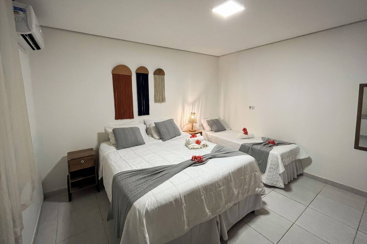 A hotel room with two beds, a nightstand, a lamp, and a ceiling light.