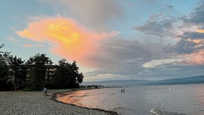 Ein Strand bei Sonnenuntergang, ruhiges Wasser und einige Personen.