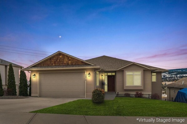 A two-story house with a garage, a front porch, and a well-maintained lawn.