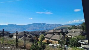 Ein Wohngebiet mit Häusern, einem Zaun und Bergen im Hintergrund.