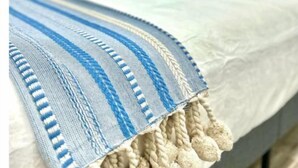 A bed with a white mattress and a blue and white striped blanket with tassels. - “NEW” Traveler’s Getaway (Pinellas Park)