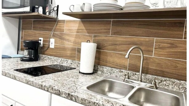 A kitchen with a granite countertop, a double sink, a coffee maker, a microwave, and a paper towel holder. - “NEW” Traveler’s Getaway (Pinellas Park)