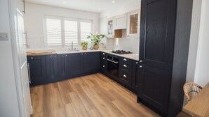 Una cocina moderna con armarios oscuros, encimera de madera y una puerta grande negra.