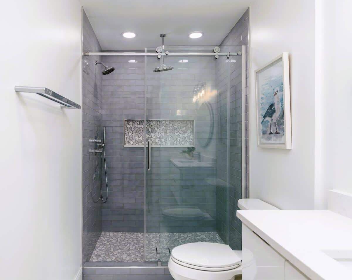 Un baño moderno con ducha envuelta en vidrio, inodoro blanco y lavabo.
