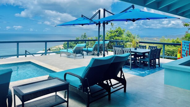 Un espace aménagé au bord de la piscine, avec des chaises longues, une table et des parasols.