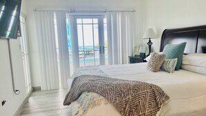 Une chambre d’hôtel avec un lit, une télévision, une table de chevet et une vue sur la plage.