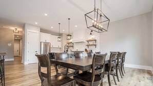 A spacious kitchen with white cabinets, a large island, and modern pendant lighting. - Timber Ridge Haus by Taylor Made Deep Creek (McHenry)