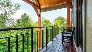 A wooden deck with a railing, overlooking a forested area. - Timber Ridge Haus by Taylor Made Deep Creek (McHenry)