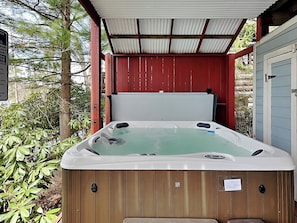 A hot tub with a wooden exterior, a metal roof, and a sign indicating a 24-hour emergency response. - Loch Haven by Taylor Made Deep Creek (McHenry)