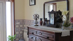 A room with a wooden dresser, a mirror, a chandelier, and a patterned rug. - Refúgio de Selores (Oliveira de Azeméis)