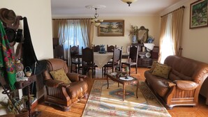 A traditional living room with leather sofas, a dining table, and a chandelier. - Refúgio de Selores (Oliveira de Azeméis)