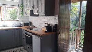 Una cucina con mobili grigi, un piano di lavoro in legno, un forno integrato e una macchina per il caffè.
