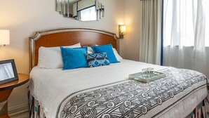 A neatly made bed with a patterned bedspread, a bedside table with a lamp, and a mirror on the wall.