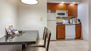 A compact kitchen with wooden cabinets, a microwave, a refrigerator, and a coffee maker.