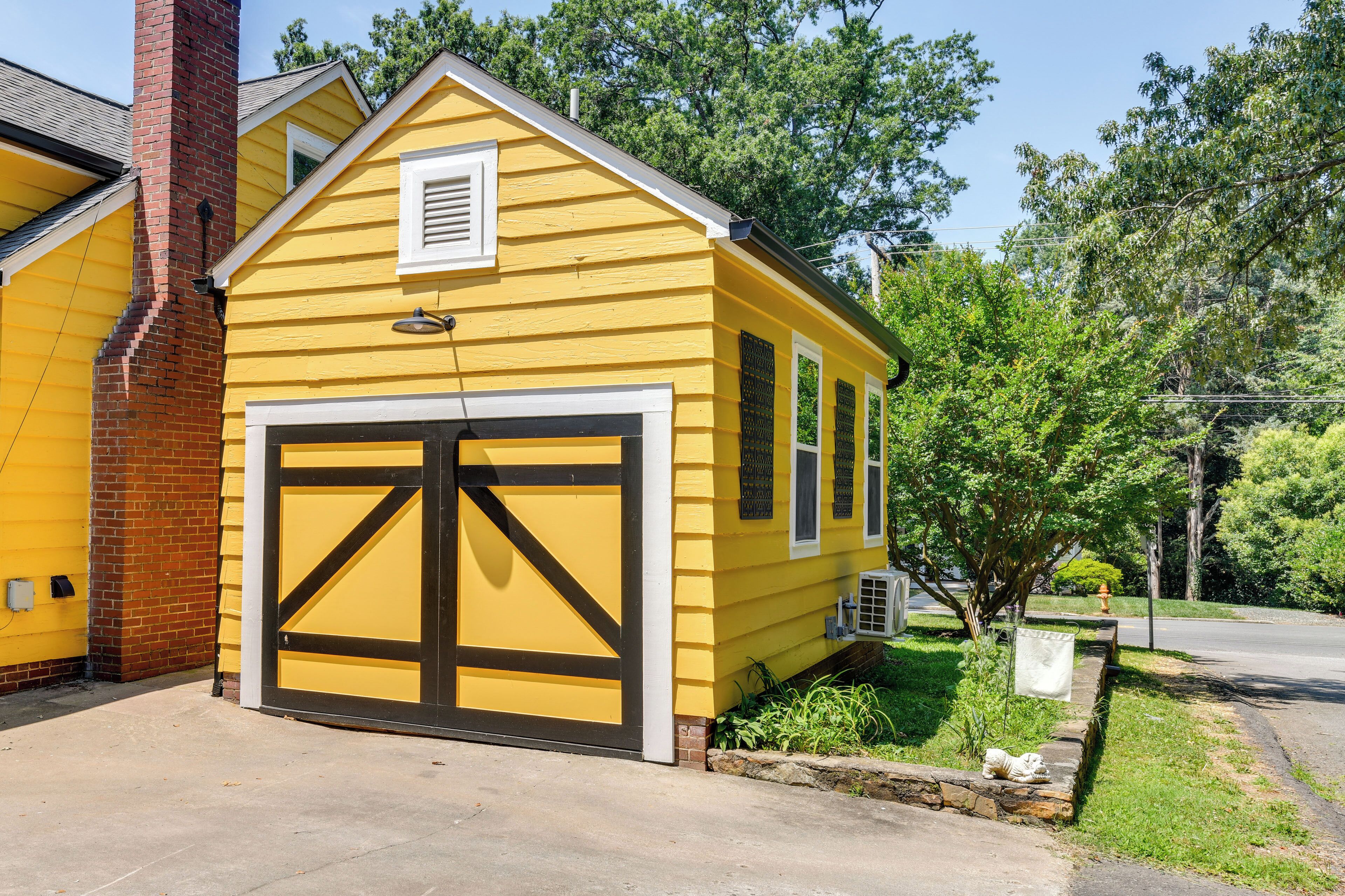 A yellow single-story house with a large garage door and a brick chimney.