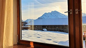 Una habitación con un amplio ventanal que ofrece vistas a un paisaje nevado y montañas.