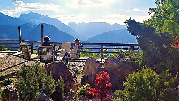 Una terraza con mesas al aire libre, con vistas a un paisaje montañoso.