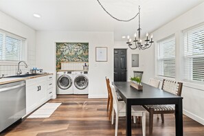 Ett modernt kök med diskmaskin, tvättmaskin och en matplats med bord och stolar.