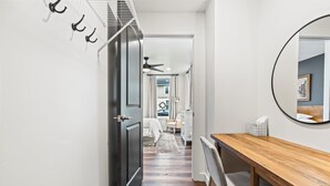 Um corredor com uma mesa de jantar de madeira, um espelho e uma porta que dá para um quarto.
