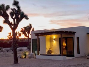 Situated in a desert landscape, this single-story building features a flat roof and minimalist design.