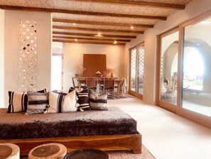 Relax in this inviting living area with a large sofa, dining table, and sliding glass door leading to an outdoor space.