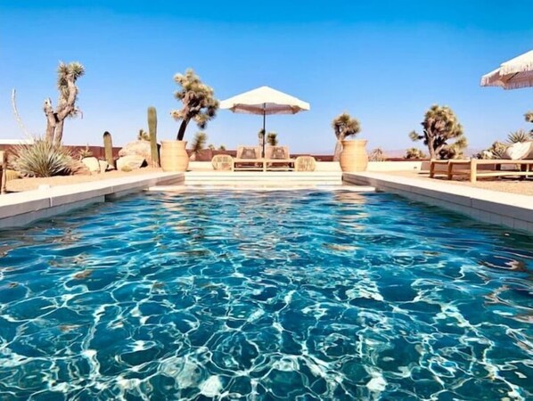 Relax by the serene pool surrounded by desert flora and lush greenery.
