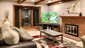 Een woonkamer met een open haard, een televisie en een bank.