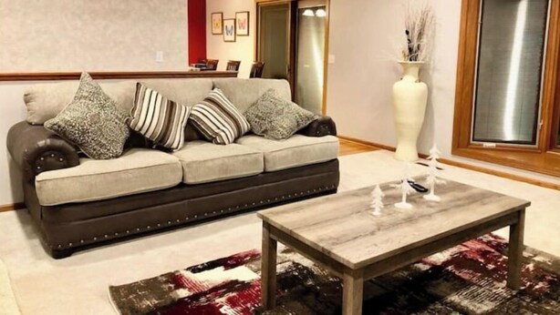 Een woonkamer met een bank, een bijzettafeltje en een vaas met decoratieve objecten.