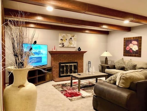 Una sala de estar con chimenea, televisor, sofá y mesa de centro.