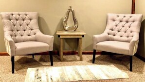 Twee fauteuils met armleuningen tegenover elkaar, met een klein tafeltje en een decoratieve vaas ertussen.