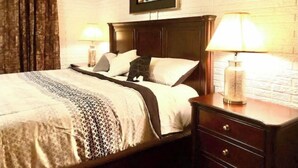 Een keurig opgeruimde hotelkamer met een groot bed, twee bedlampen, een houten nachtkastje en een lijst met een afbeelding boven het bed.