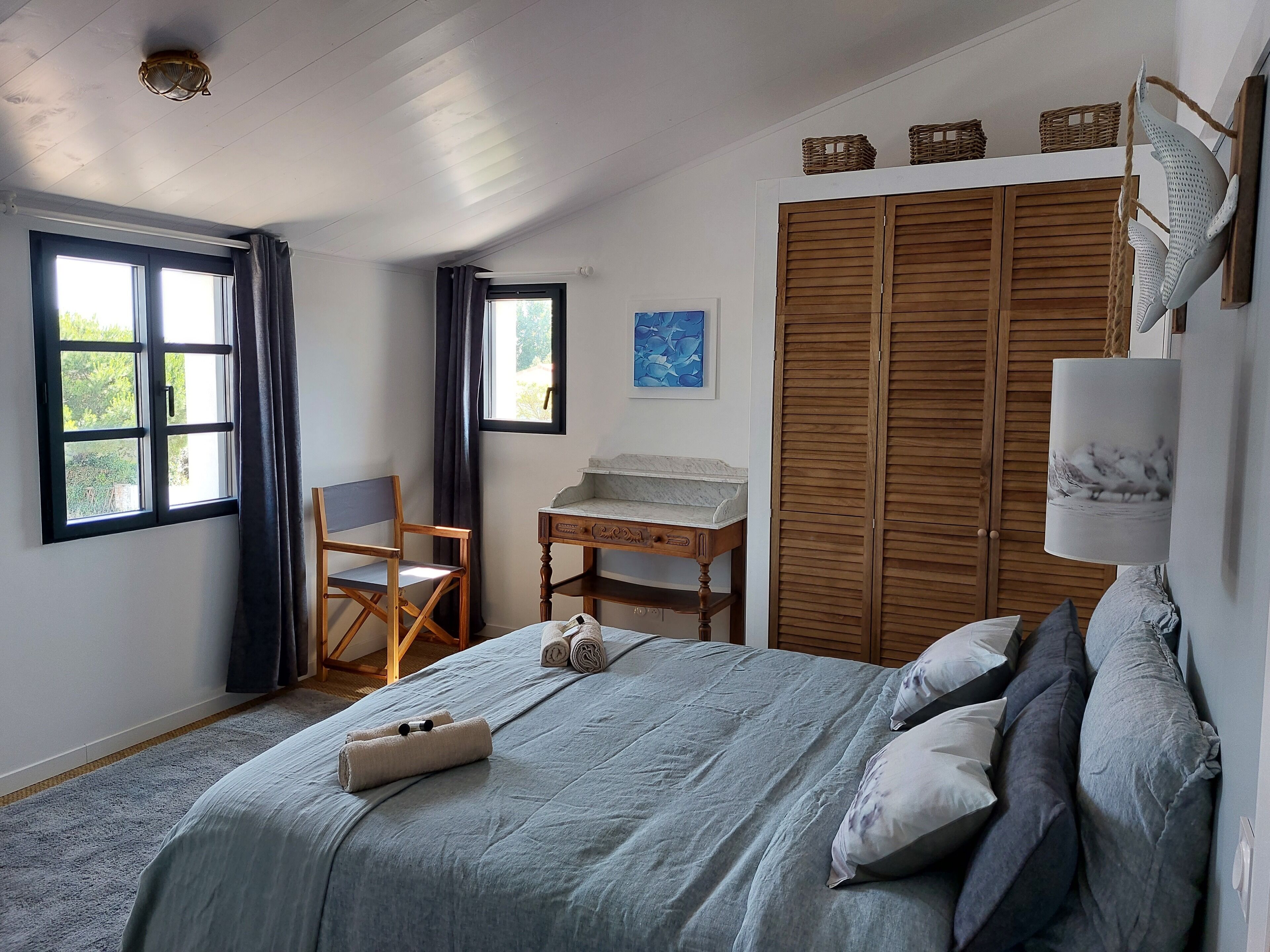 Un dormitorio con cama, escritorio, silla, armario y ventana.